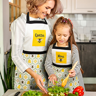 A woman and girl in aprons cooking
